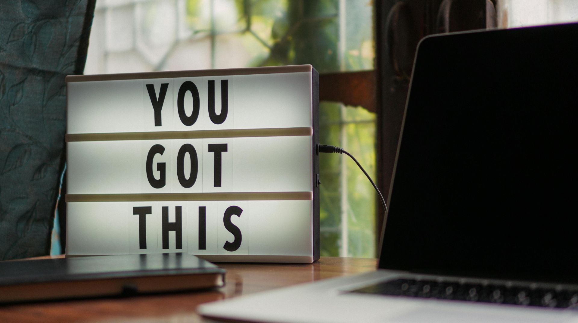 Lit sign with 'You Got This' alongside laptop on office desk.