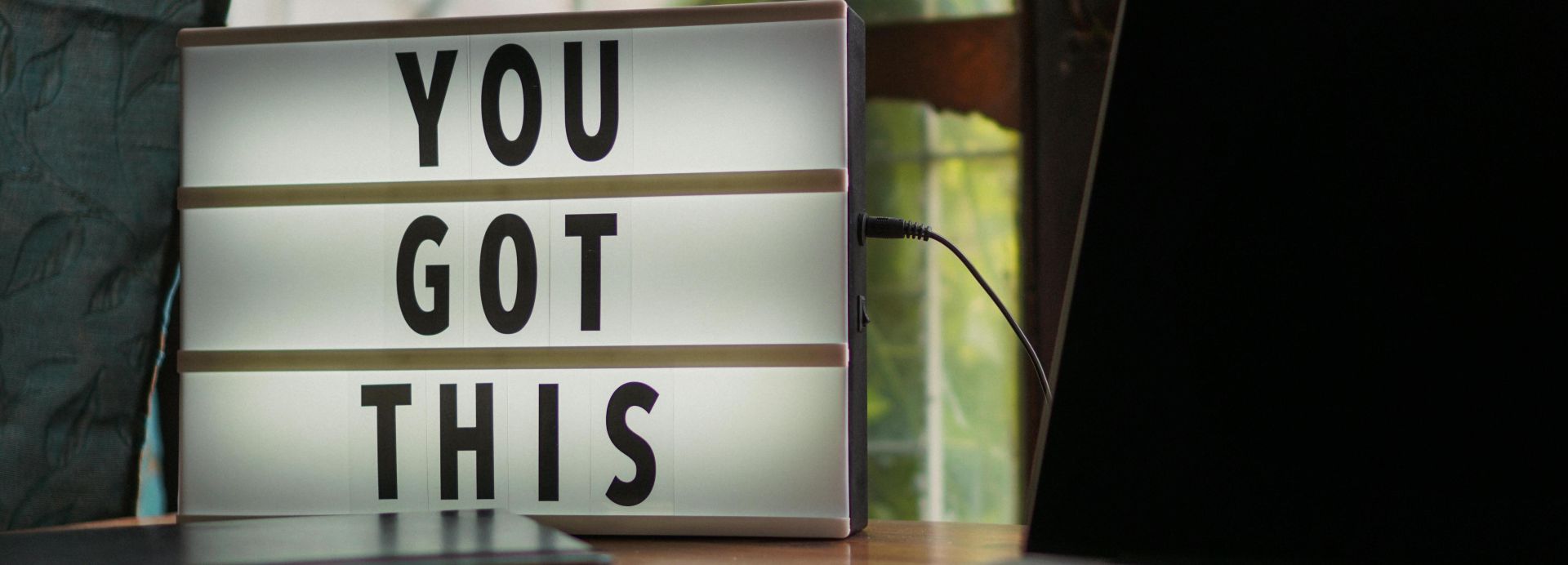 Lit sign with 'You Got This' alongside laptop on office desk.